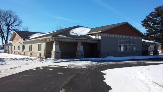 Snowy exterior of a single-story facility with a covered entrance and paved driveway.