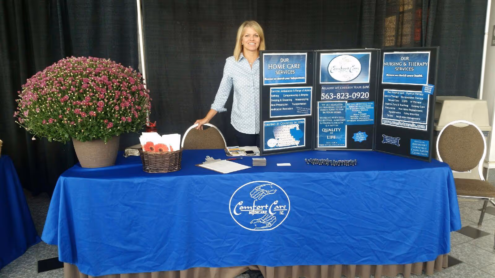 A promotional booth for Comfort Care Medicare with a blue tablecloth and informational boards.
