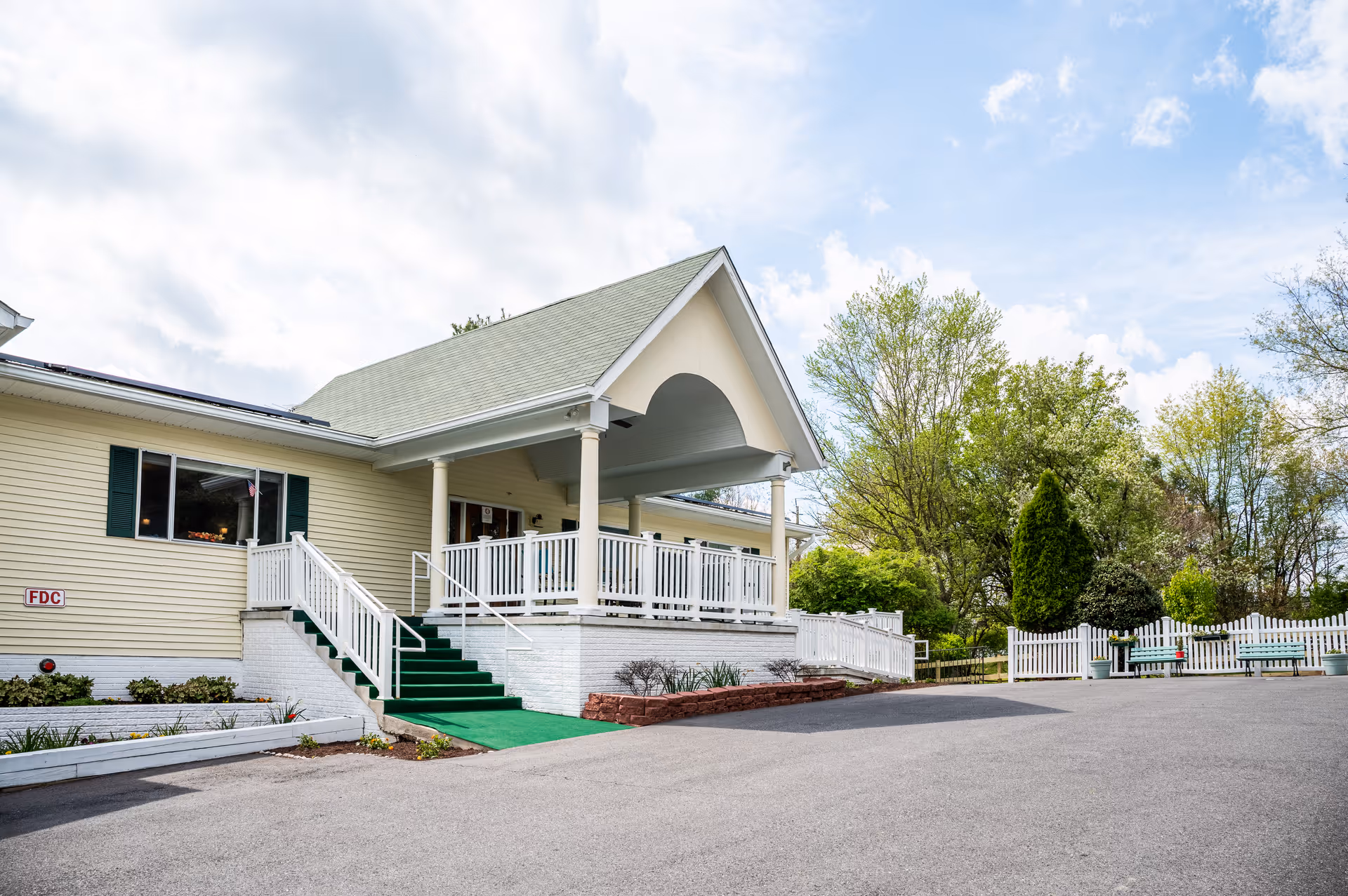 Exterior of AlfredHouse I senior living facility featuring a covered porch and green stairs.