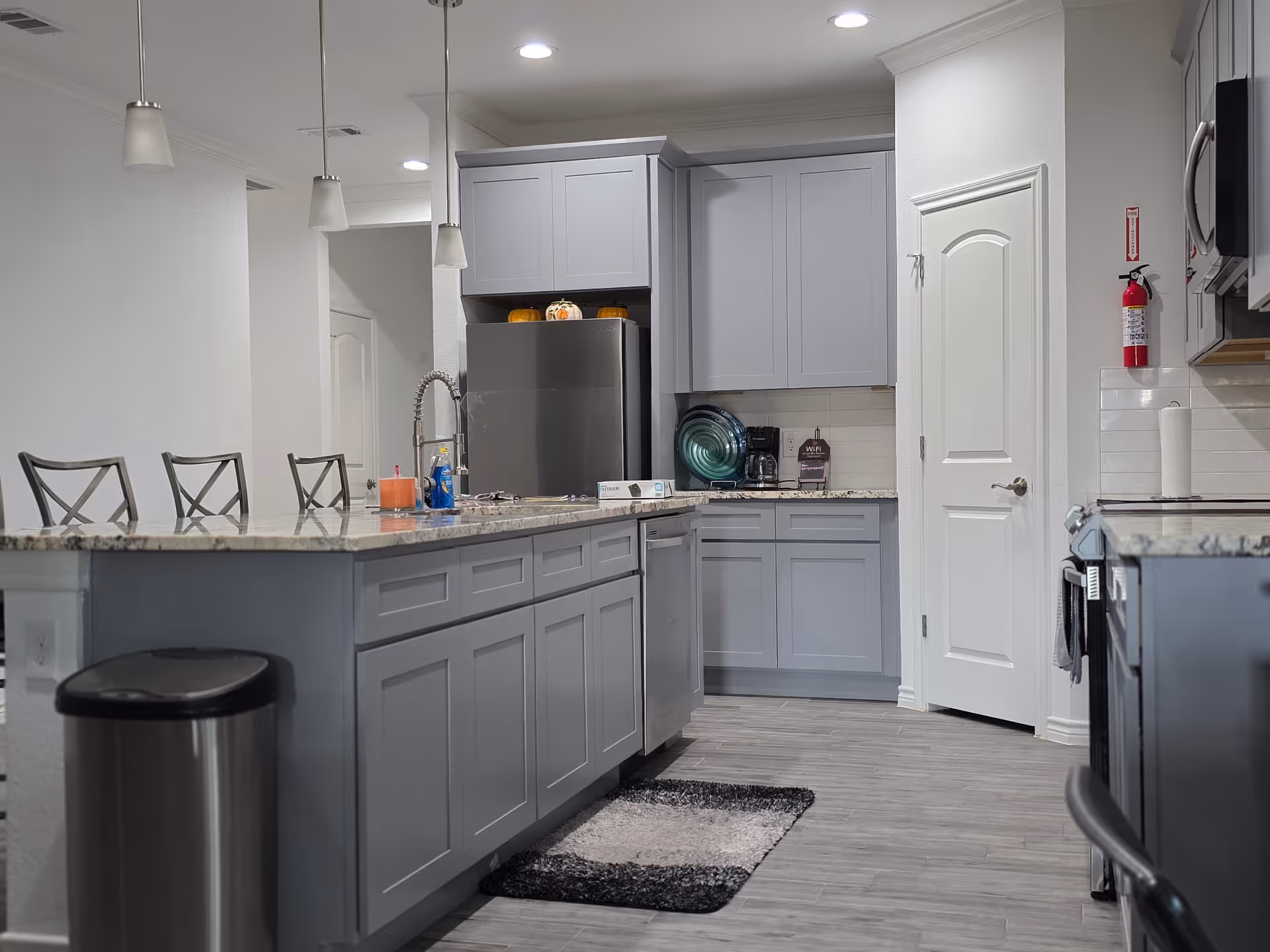 Modern gray kitchen with island, stainless steel appliances, and pendant lights.