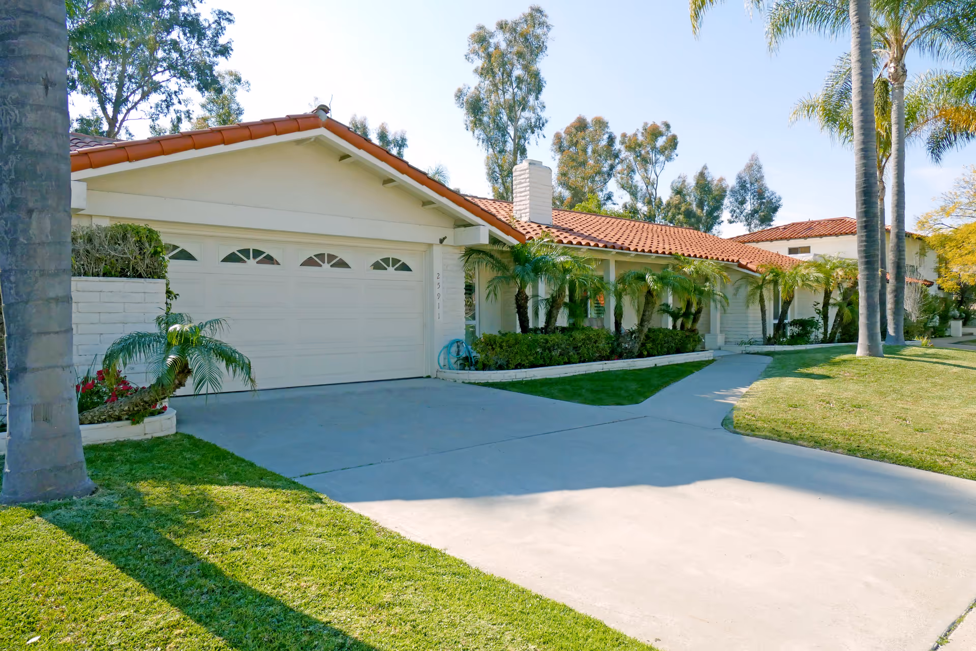 Exterior view of Aspen Villa senior living community with garages and palm trees.