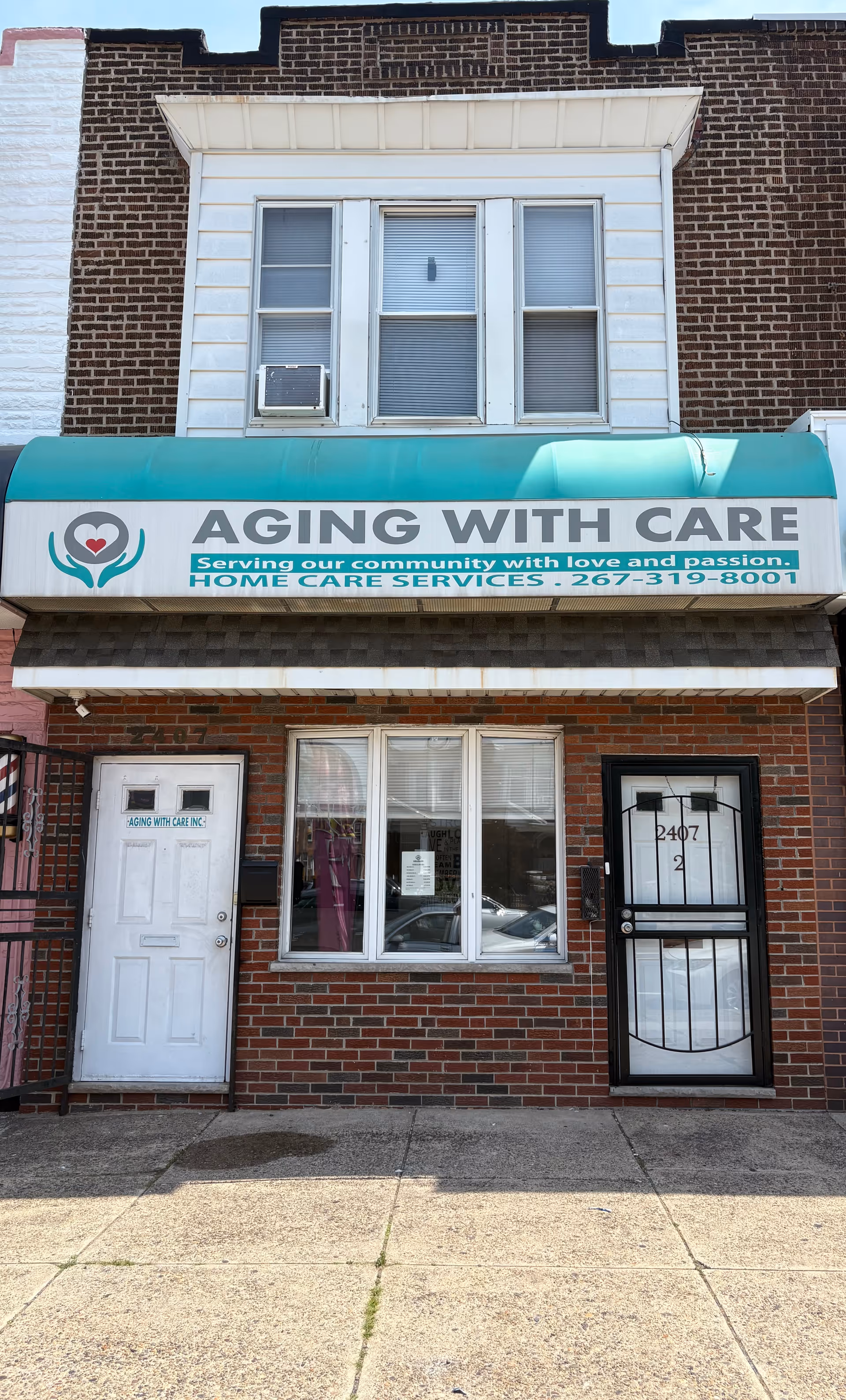 Brick storefront with teal awning and a sign for Aging With Care home care services.