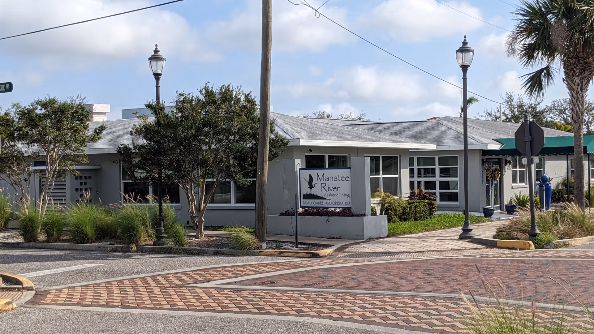 Exterior view of Manatee River Assisted Living with sign, walkway, and landscaping.