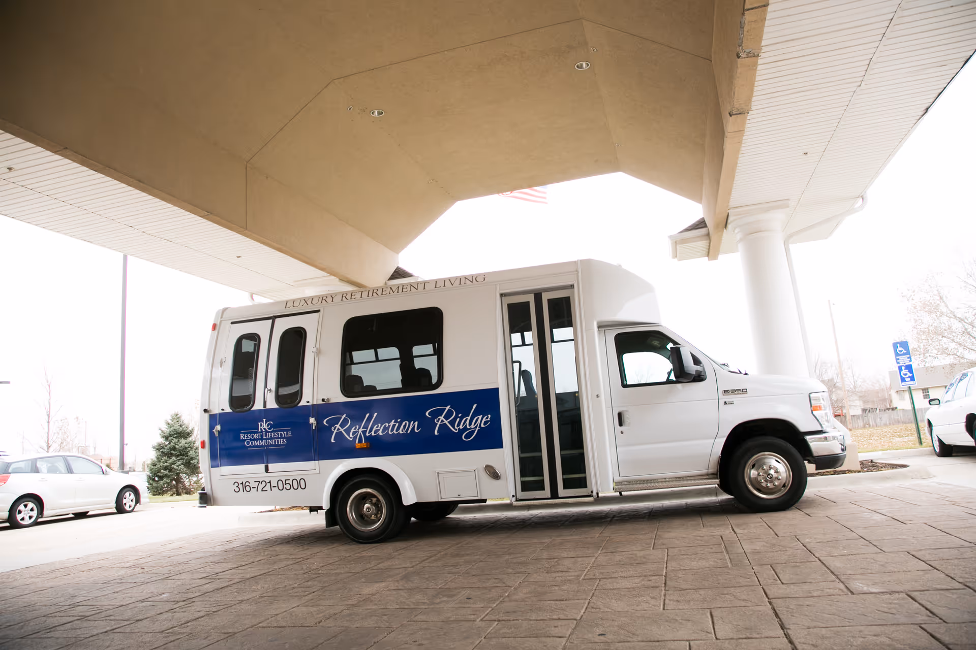 White shuttle bus with Reflection Ridge branding parked under a building canopy