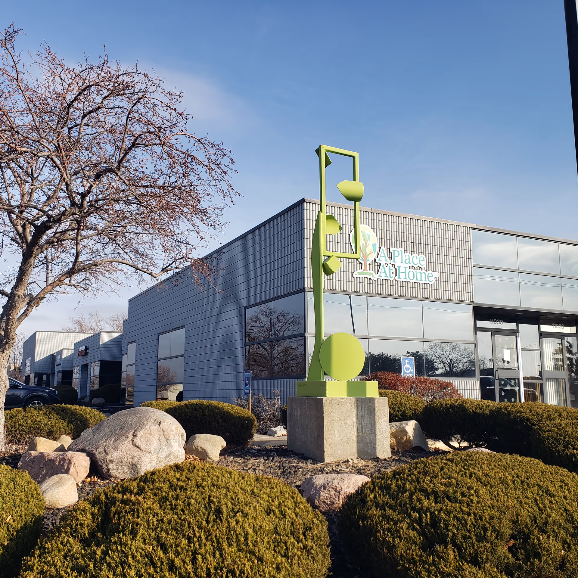 Exterior view of A Place At Home Omaha featuring a lime sculpture and manicured landscaping.