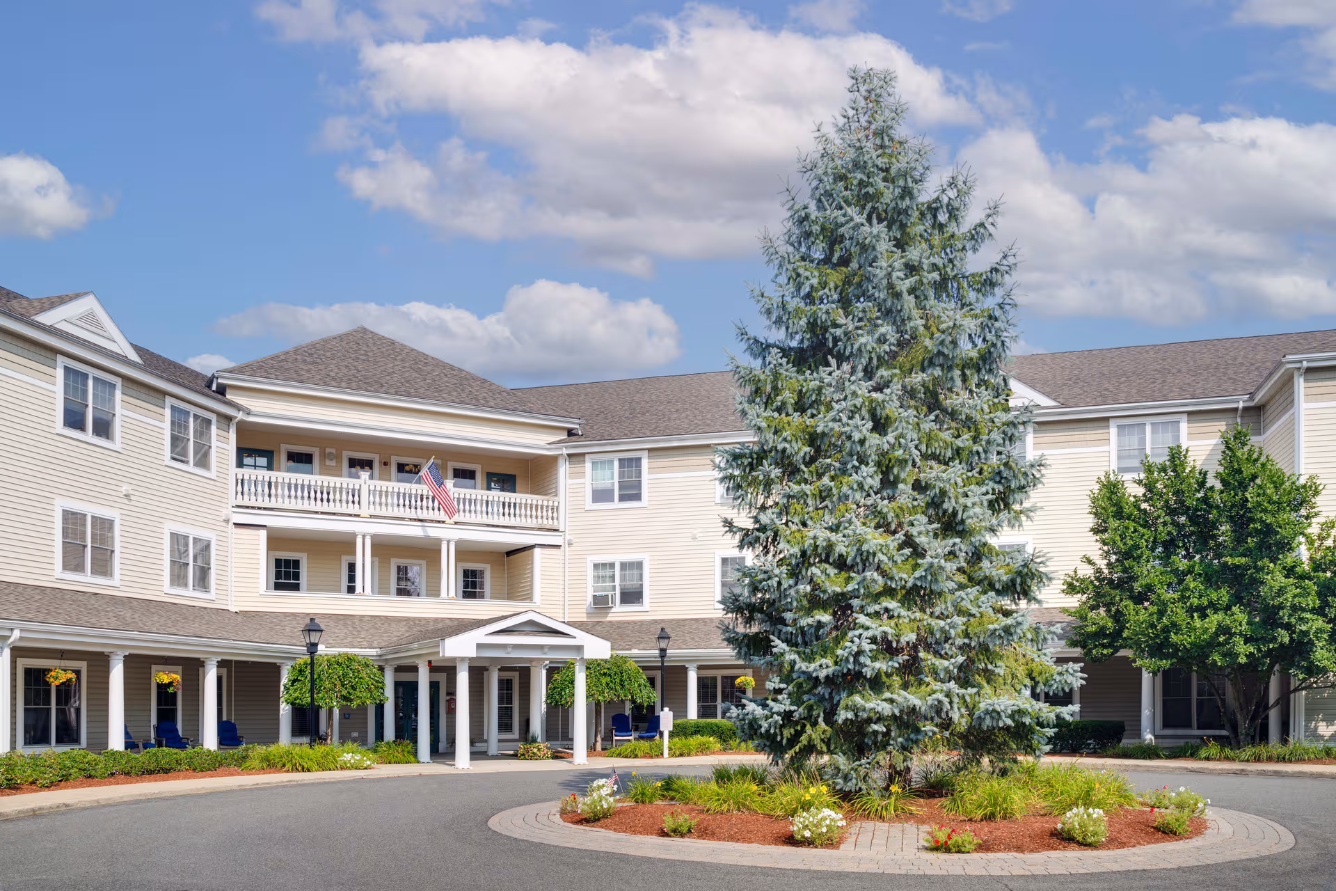 Exterior view of Traditions of Dedham building with circular driveway and landscaping