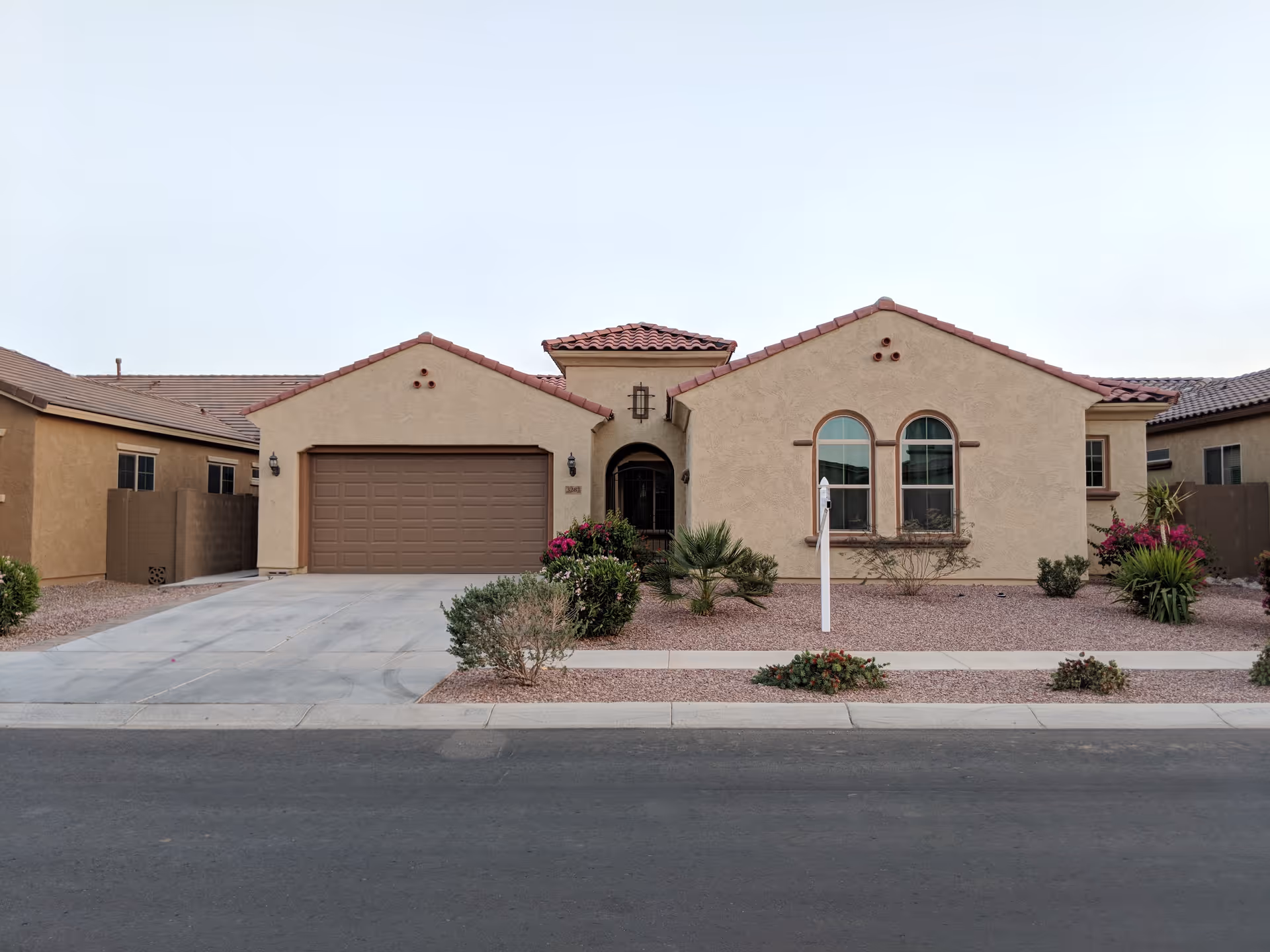 A single-story stucco building with a two-car garage and desert landscaping in front.