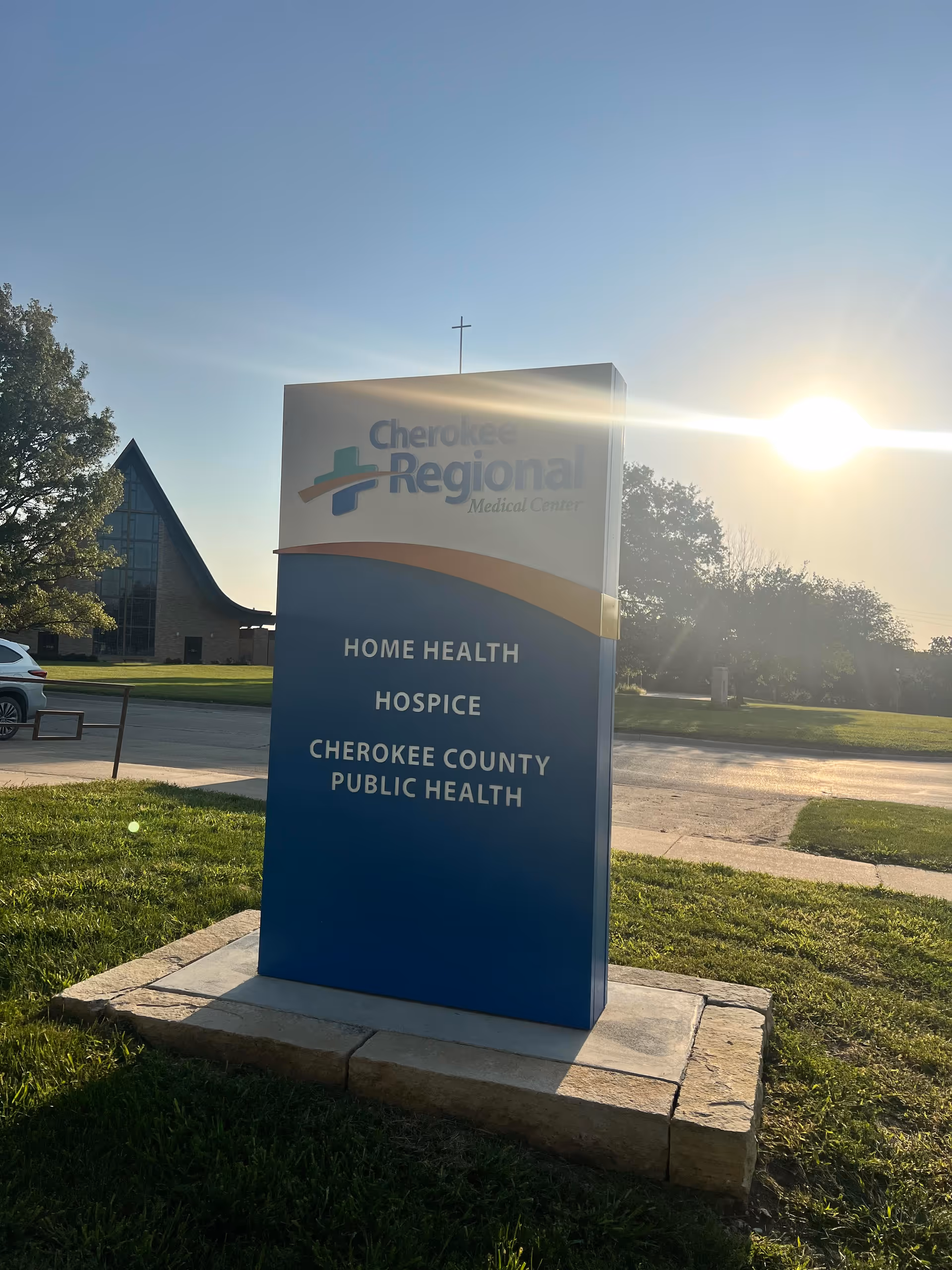 A large exterior sign for Cherokee Regional Hospice outdoors near a sunny building