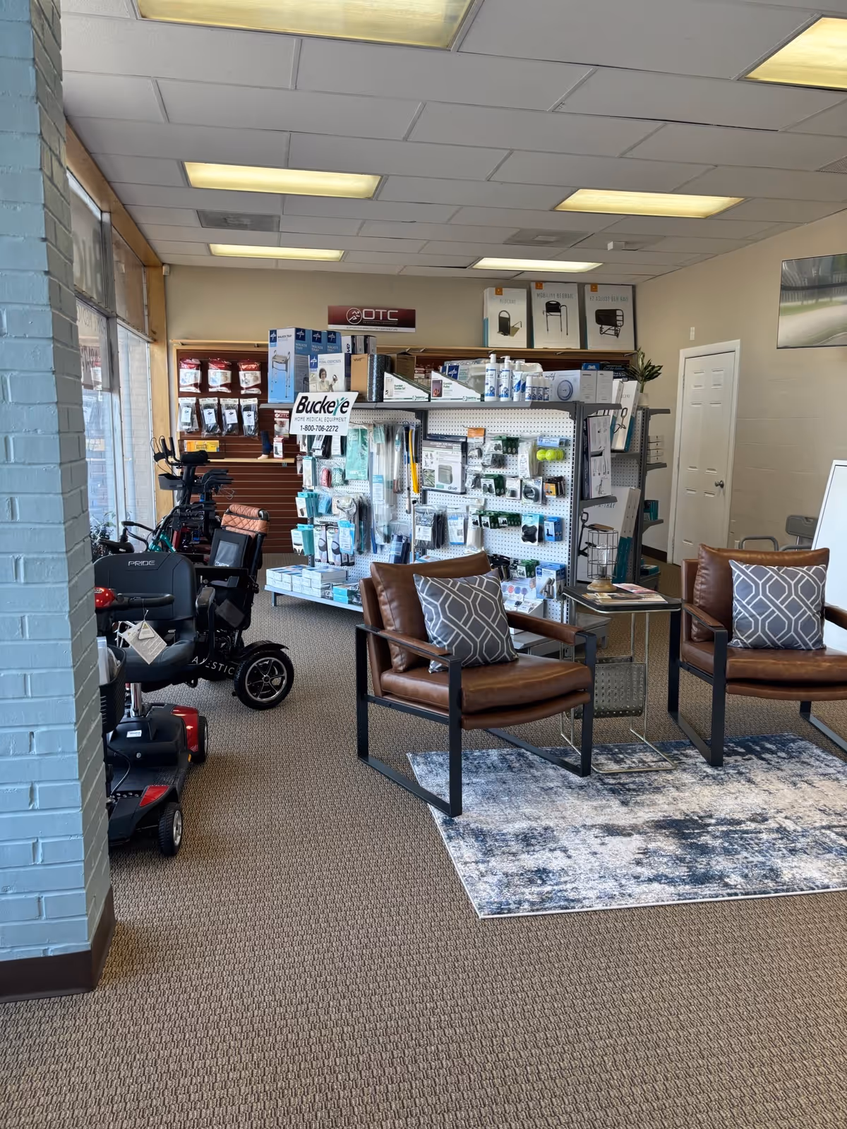 Interior showroom with medical supplies, display shelves, and two brown leather chairs on a patterned rug.