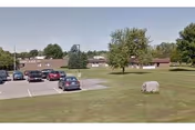 Parking lot in front of Orchard Rehabilitation and Nursing Center with trees and lawn.