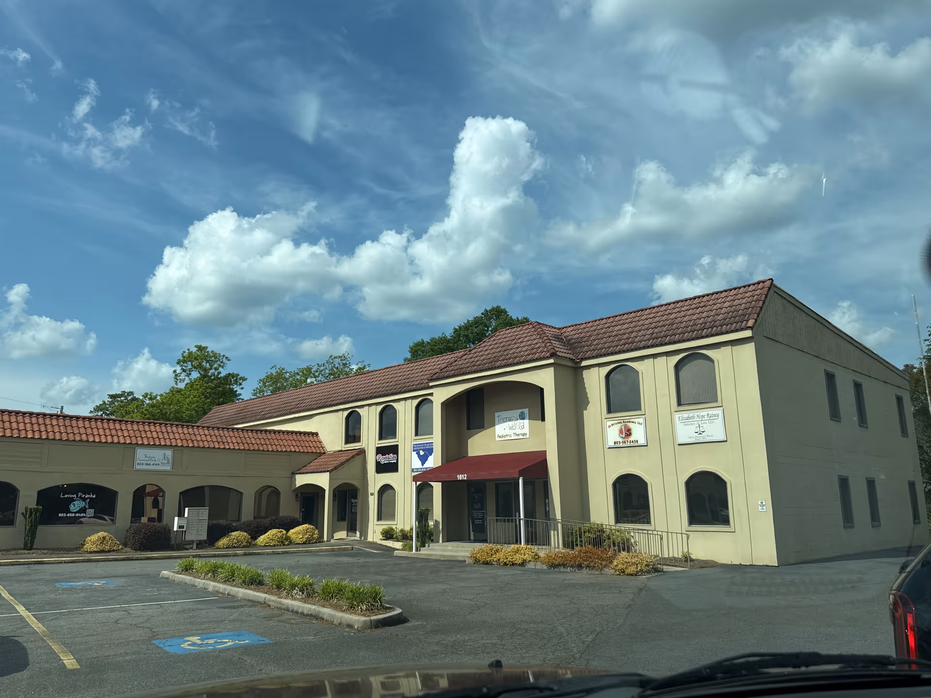 Exterior view of Therapy World building with beige walls, red roof, and parking lot.