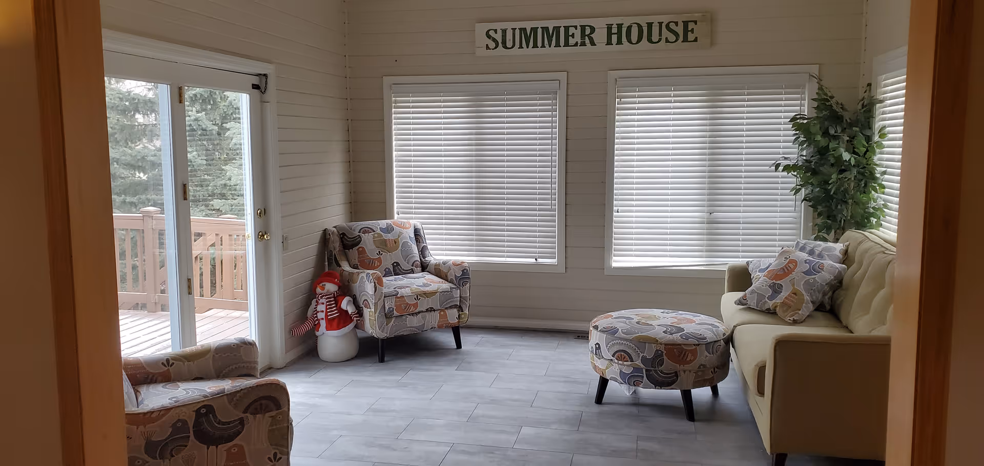 Bright lounge area with chairs, sofa, ottoman, and a sign Summer House.
