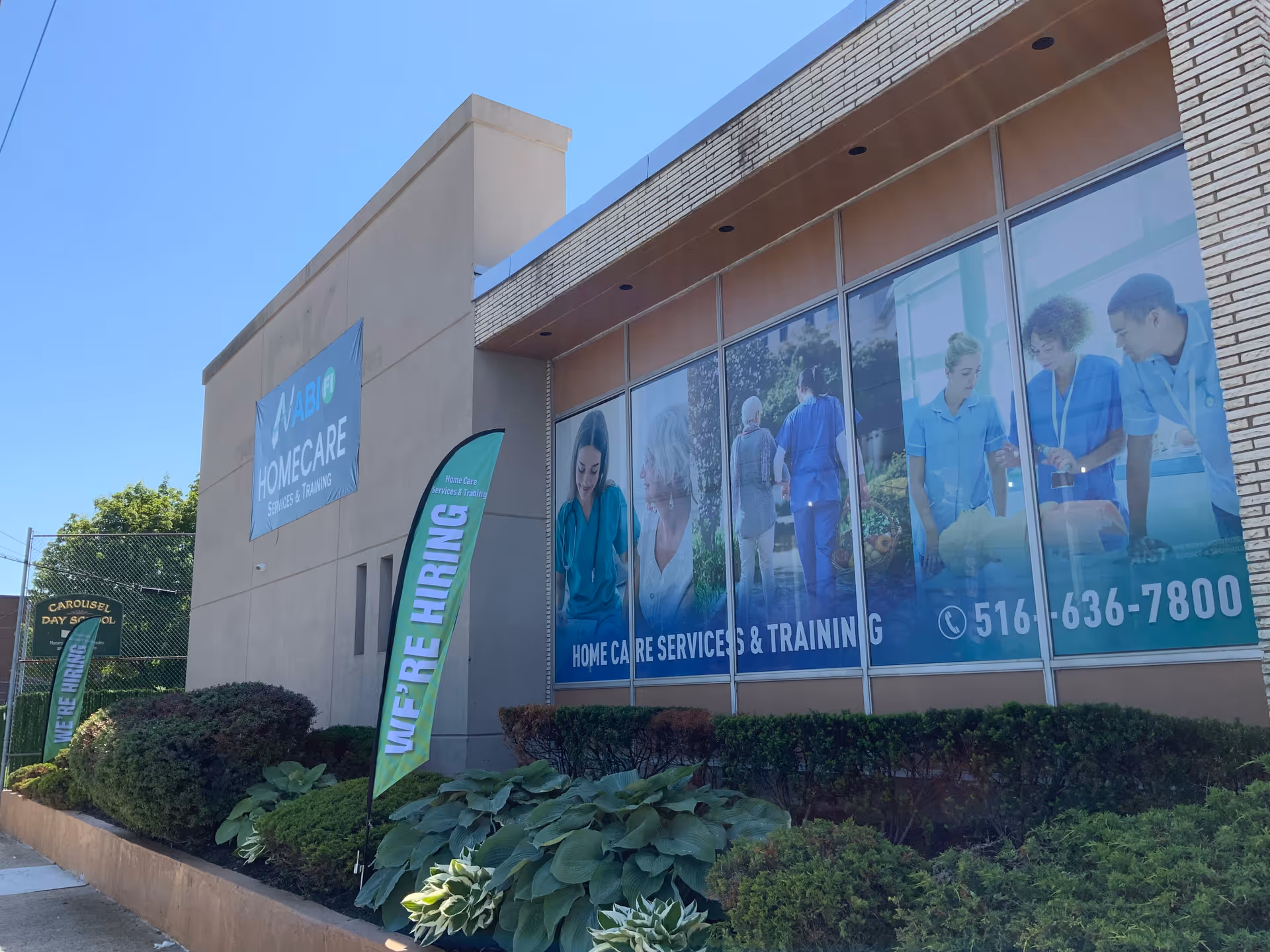 Exterior view of ABI Health Care office with hiring banners along glass windows