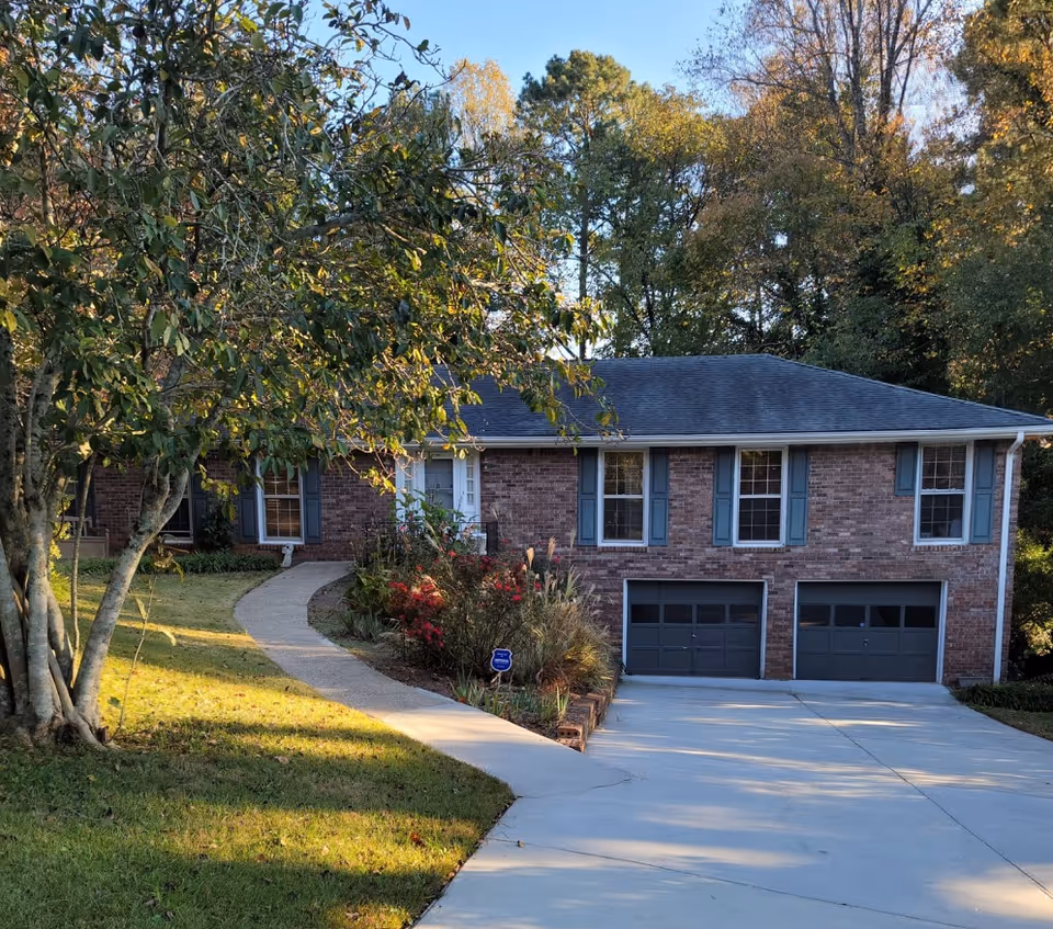 Brick senior living facility exterior with a curved walkway, two-car garage, and landscaping.