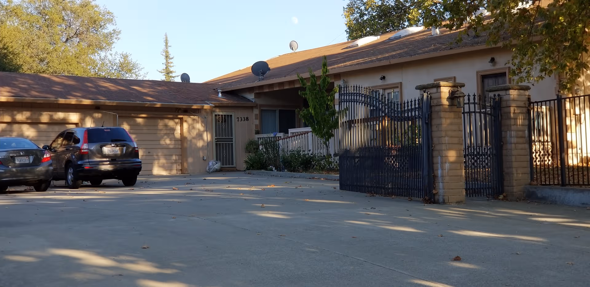 Gated entrance to a single-story care facility with parked cars and driveway.