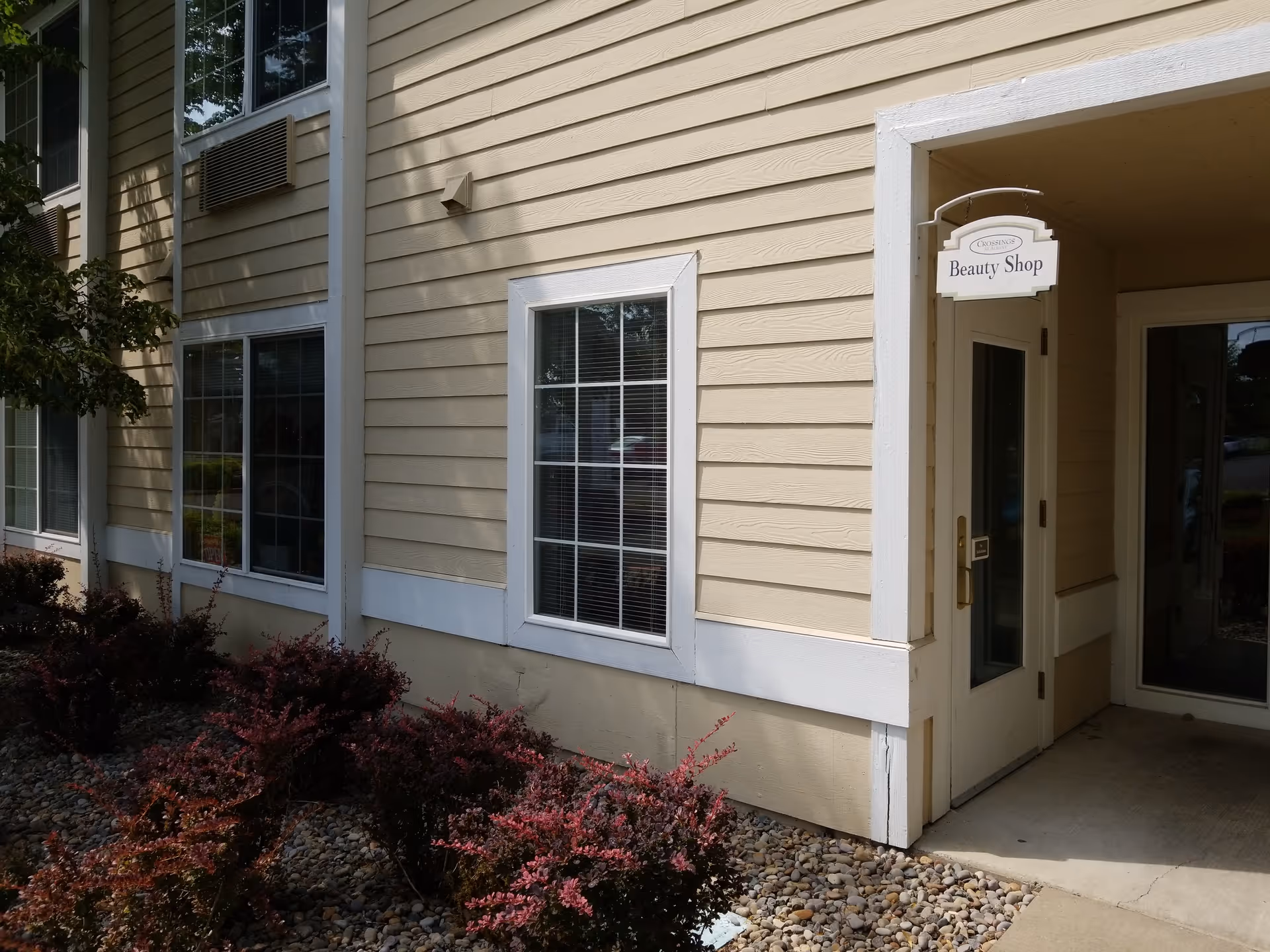 Exterior view of a beige senior living building with a Beauty Shop sign near the entrance