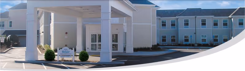 Front entrance of the Belair Care Center showing a covered porte-cochère, driveway, and the adjacent two-story building.
