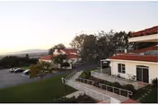 Exterior view of Marycrest Manor with white walls, red roof, ramp, and parking.