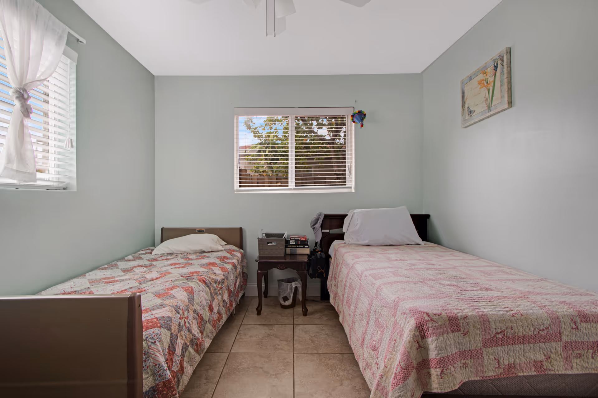Two twin beds with patchwork quilts in a light blue bedroom.