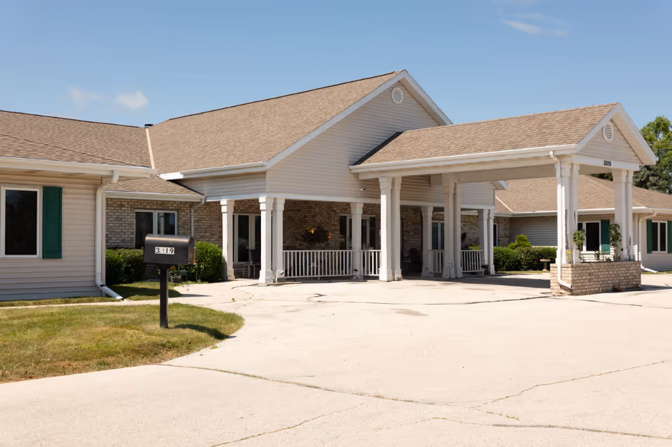 Exterior view of The Shores of Sheboygan Senior Living entrance with a covered driveway and columns.