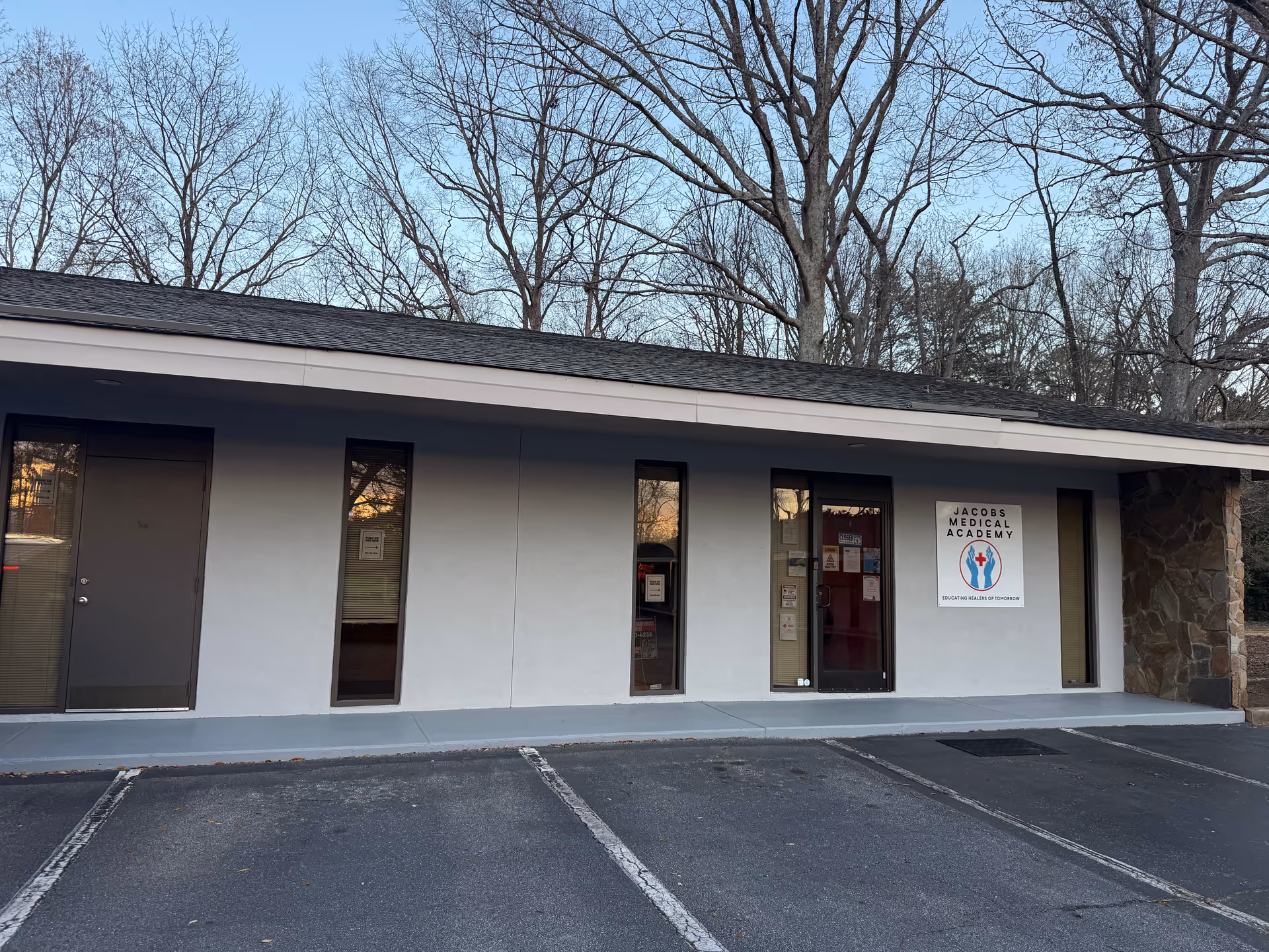 Front view of a single-story medical building with glass entry doors beside a parking lot.