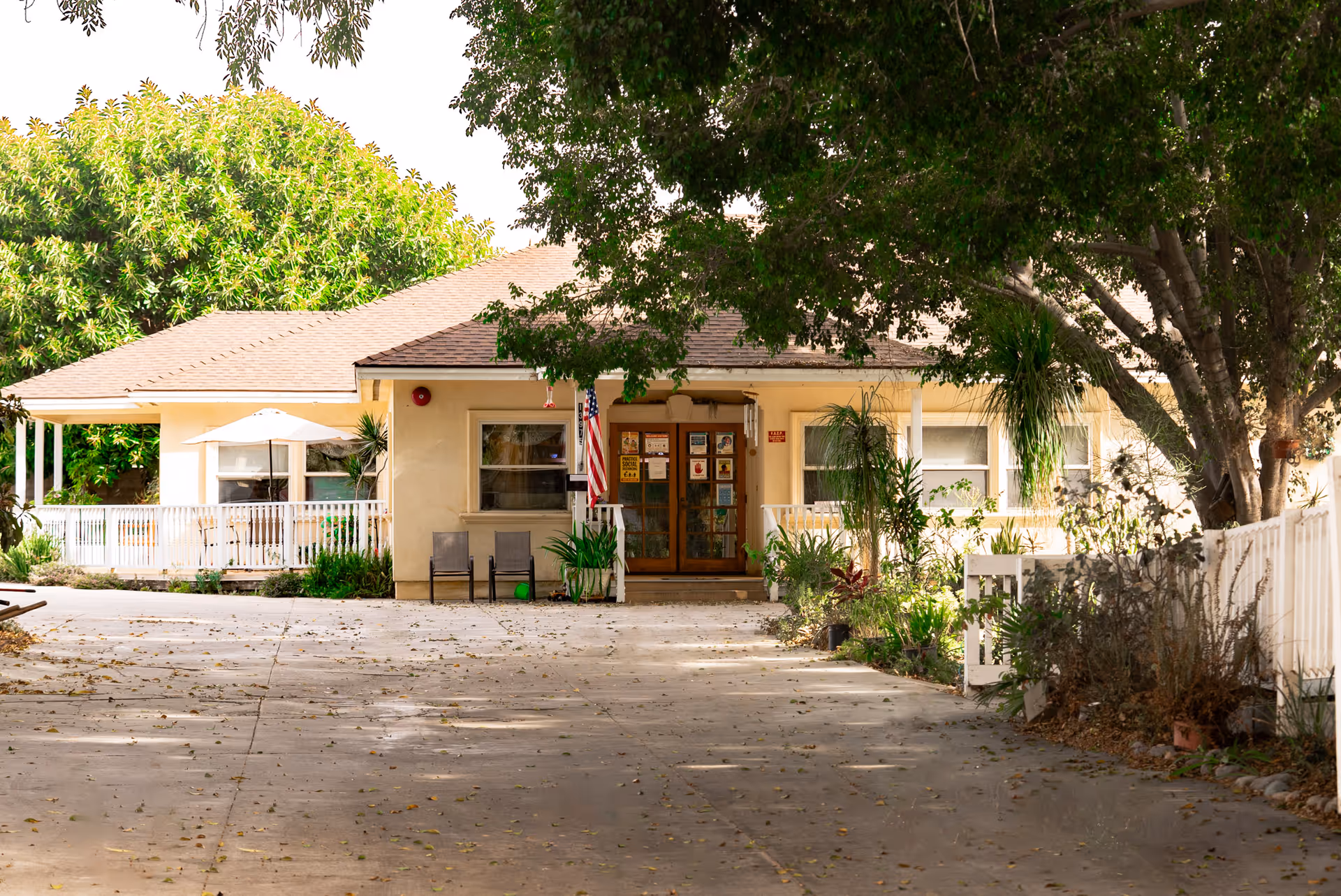Walnut Villa senior living facility entrance with flag, chairs, and greenery.