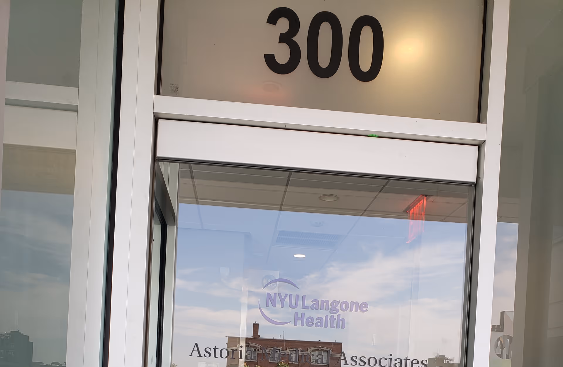 Glass entrance door showing NYU Langone Health logo and Astoria Medical Associates signage.