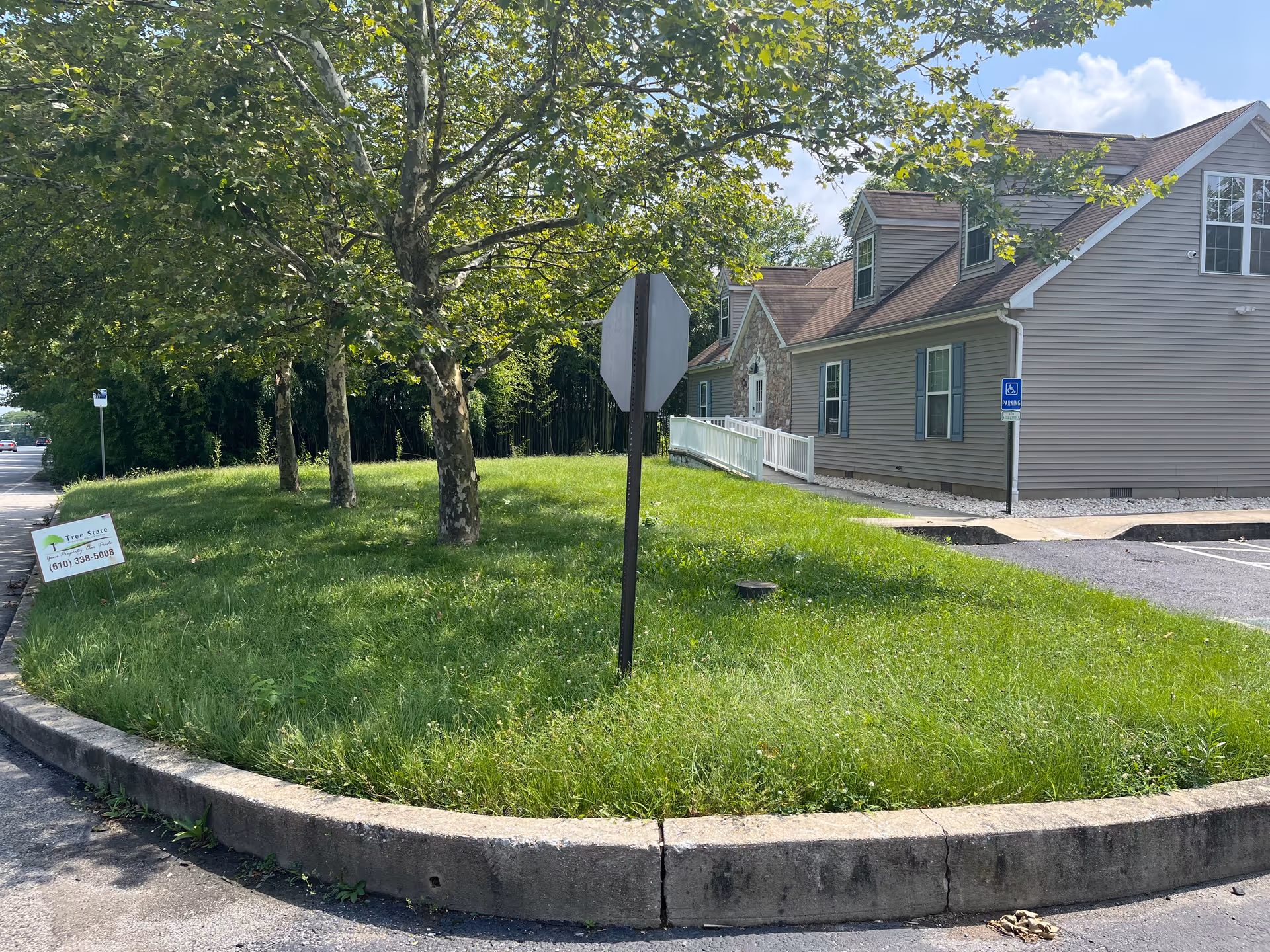 Grassy median with trees beside a beige residential building and a ramp.