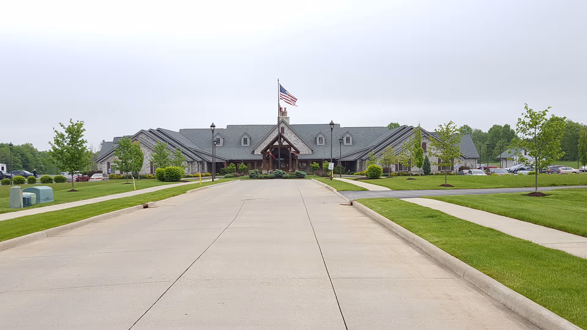 Wide driveway leads to the front entrance of a senior living center with a flag.