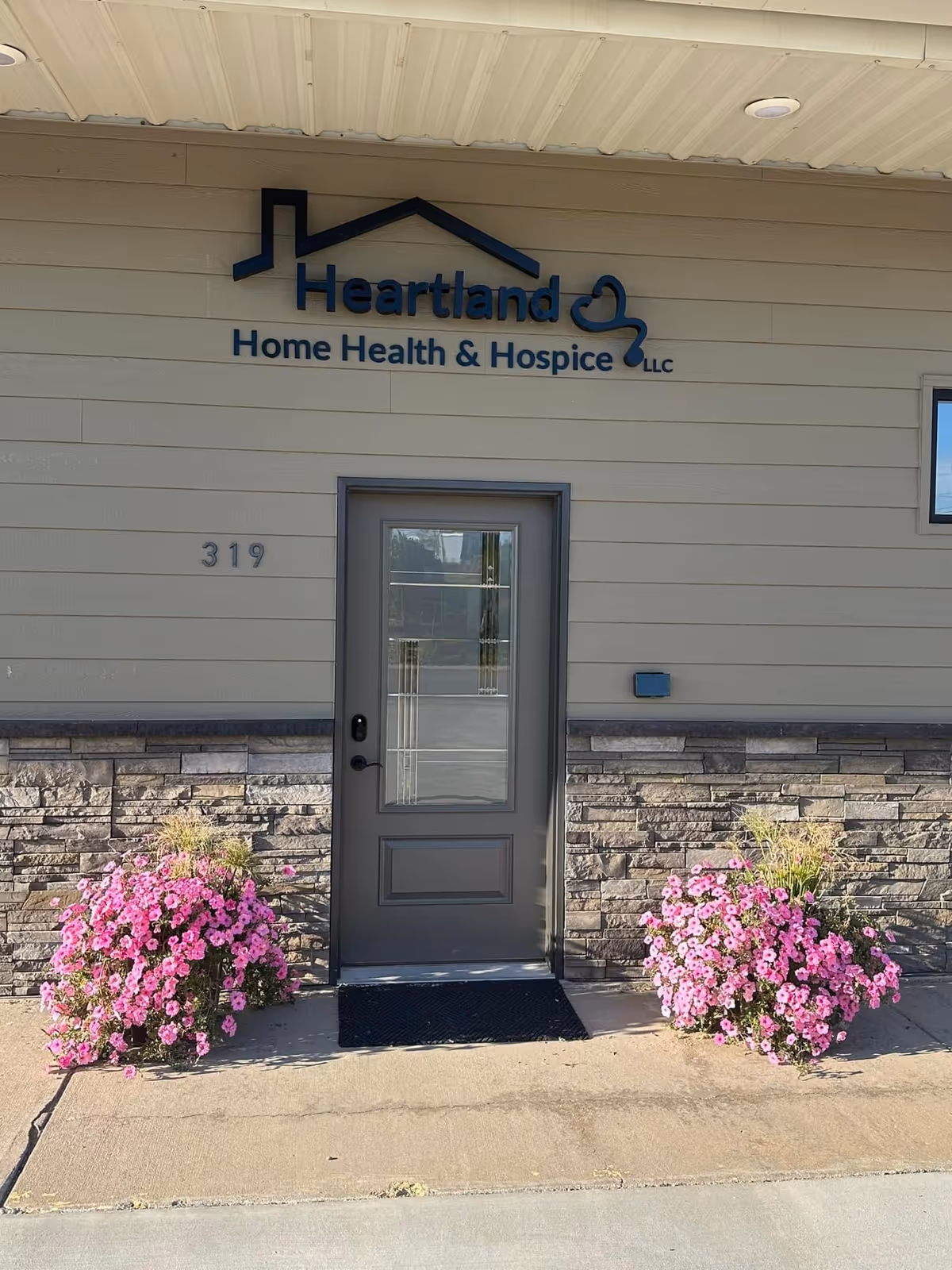 Front entrance of Heartland Home Health & Hospice with pink flowering planters.