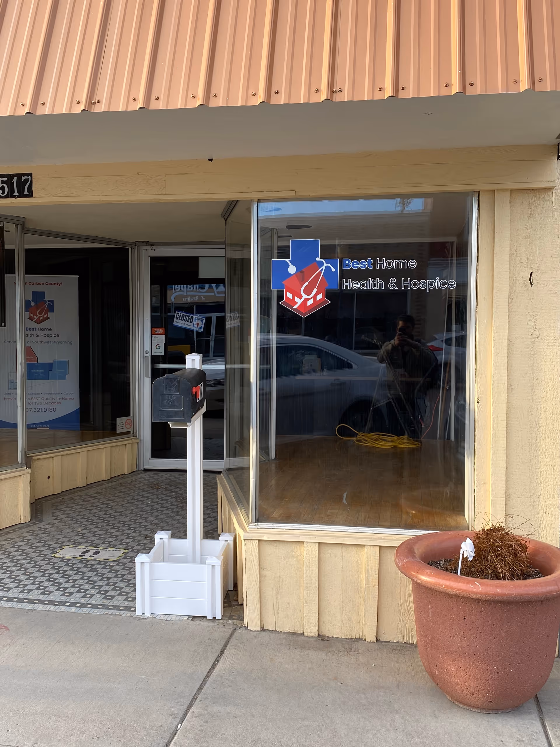 Front exterior of Best Home Health & Hospice storefront with glass door and potted plant.