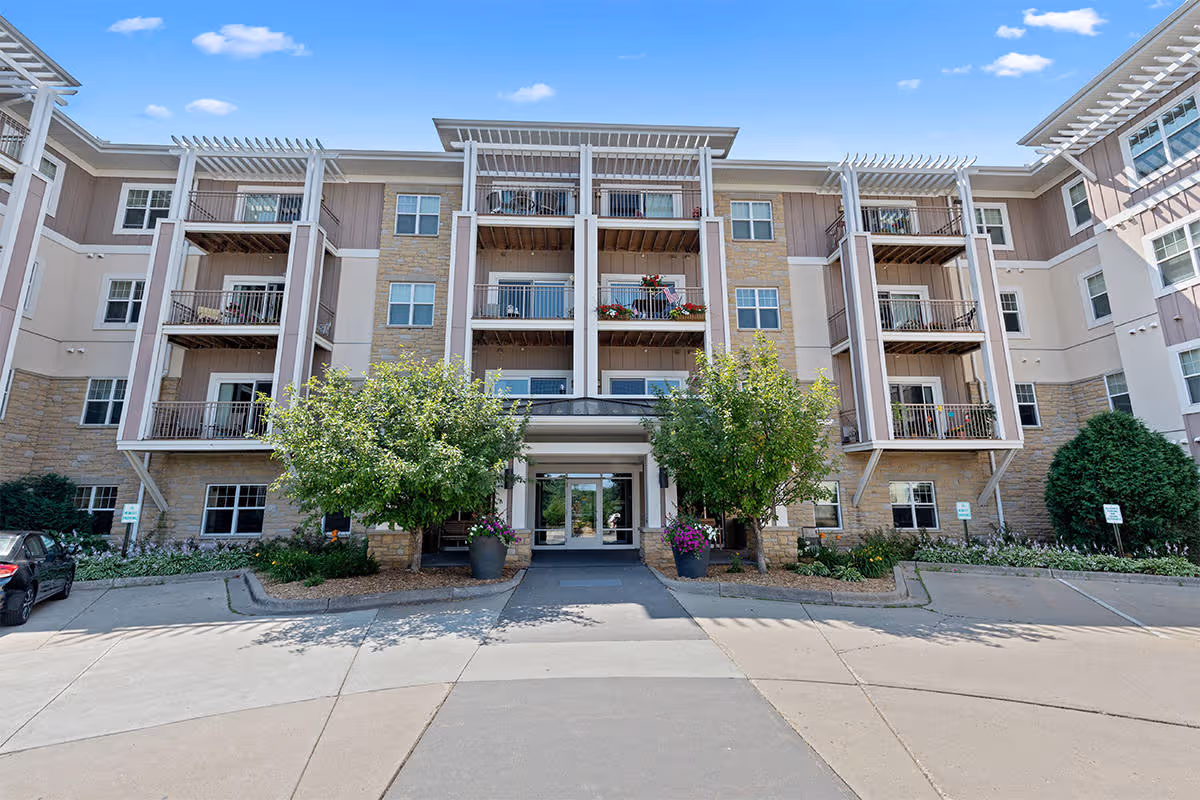 Front view of a multi-story senior living building with balconies and landscaping.