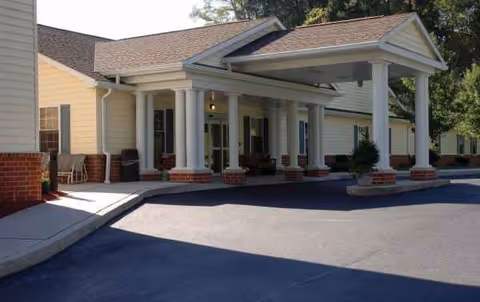 A single-story senior living facility with a covered front entrance, white columns, and brick accents.