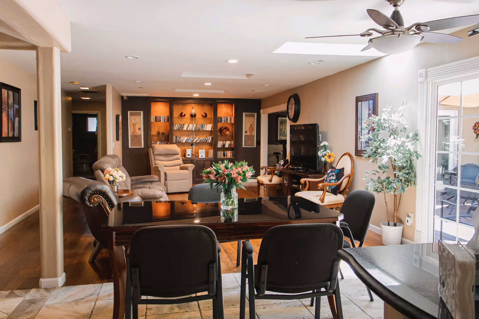 Interior common area featuring a dining table, chairs, couches, bookshelf, TV, and plants.