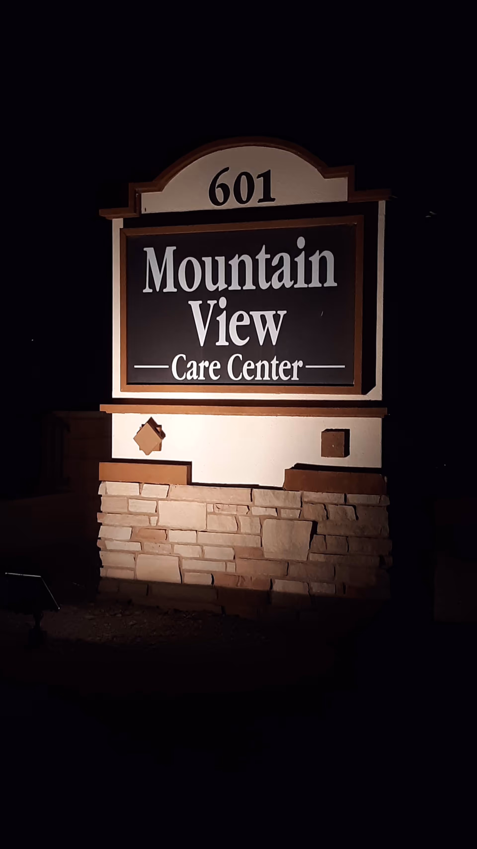 Night exterior sign reads Mountain View Care Center atop a stone base.