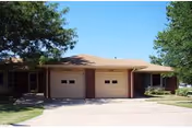 Front view of a single-story brick senior living building with two garage bays.