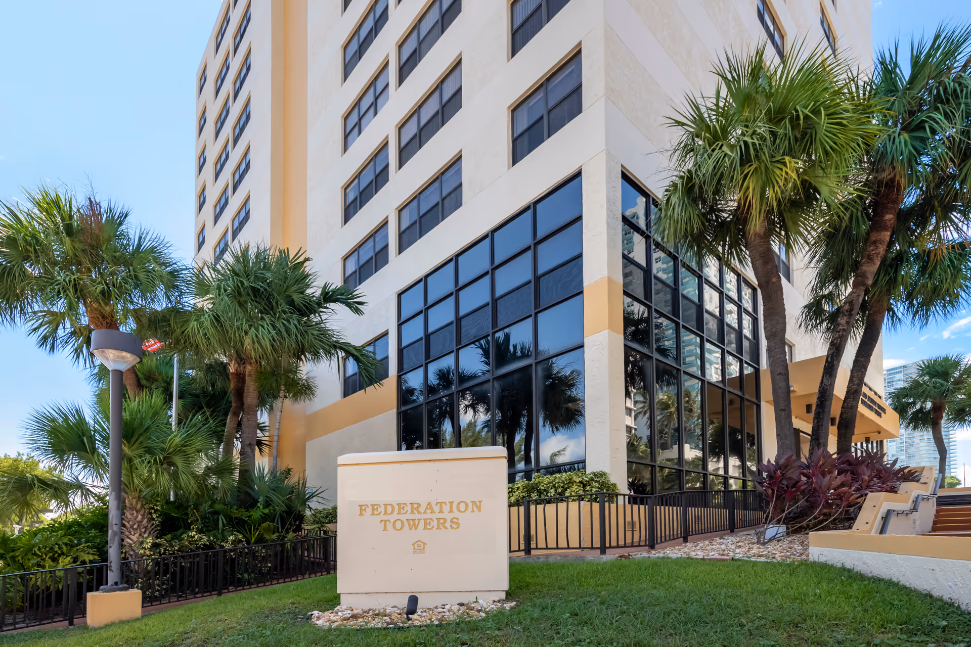 Exterior view of Federation Towers with palm trees and an entrance sign.