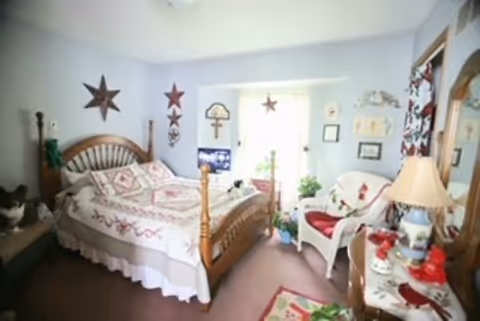 Cozy pastel bedroom with a wooden four-poster bed, seating area, and star decor.