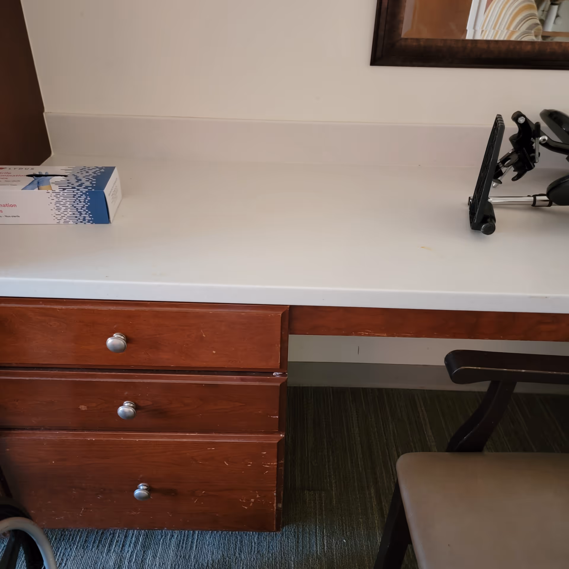Interior office desk with wooden drawers, chair, and medical equipment.