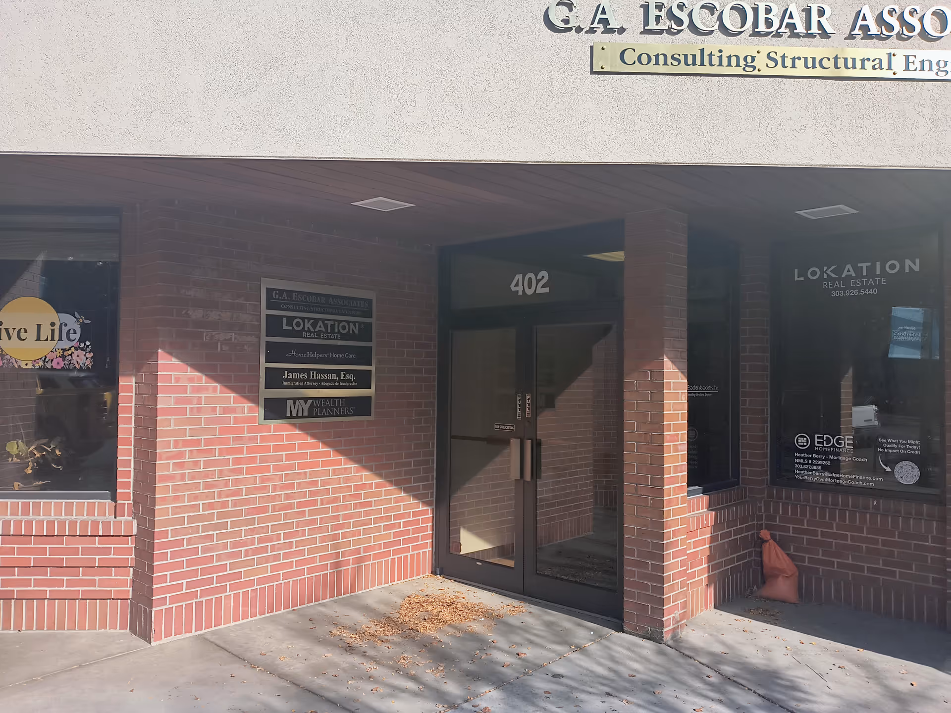 Brick storefront entrance with glass doors, numbered 402, and signs on the wall.