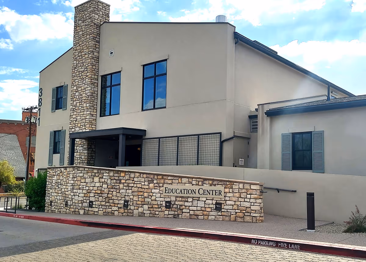 Exterior view of a modern building with a stone wall and Education Center sign.