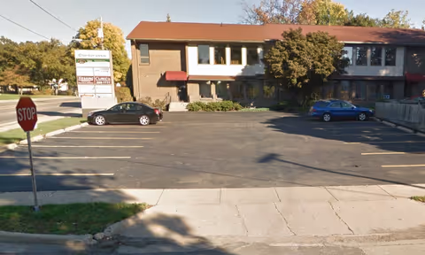 Exterior view of a brick senior care facility with parking lot and sign