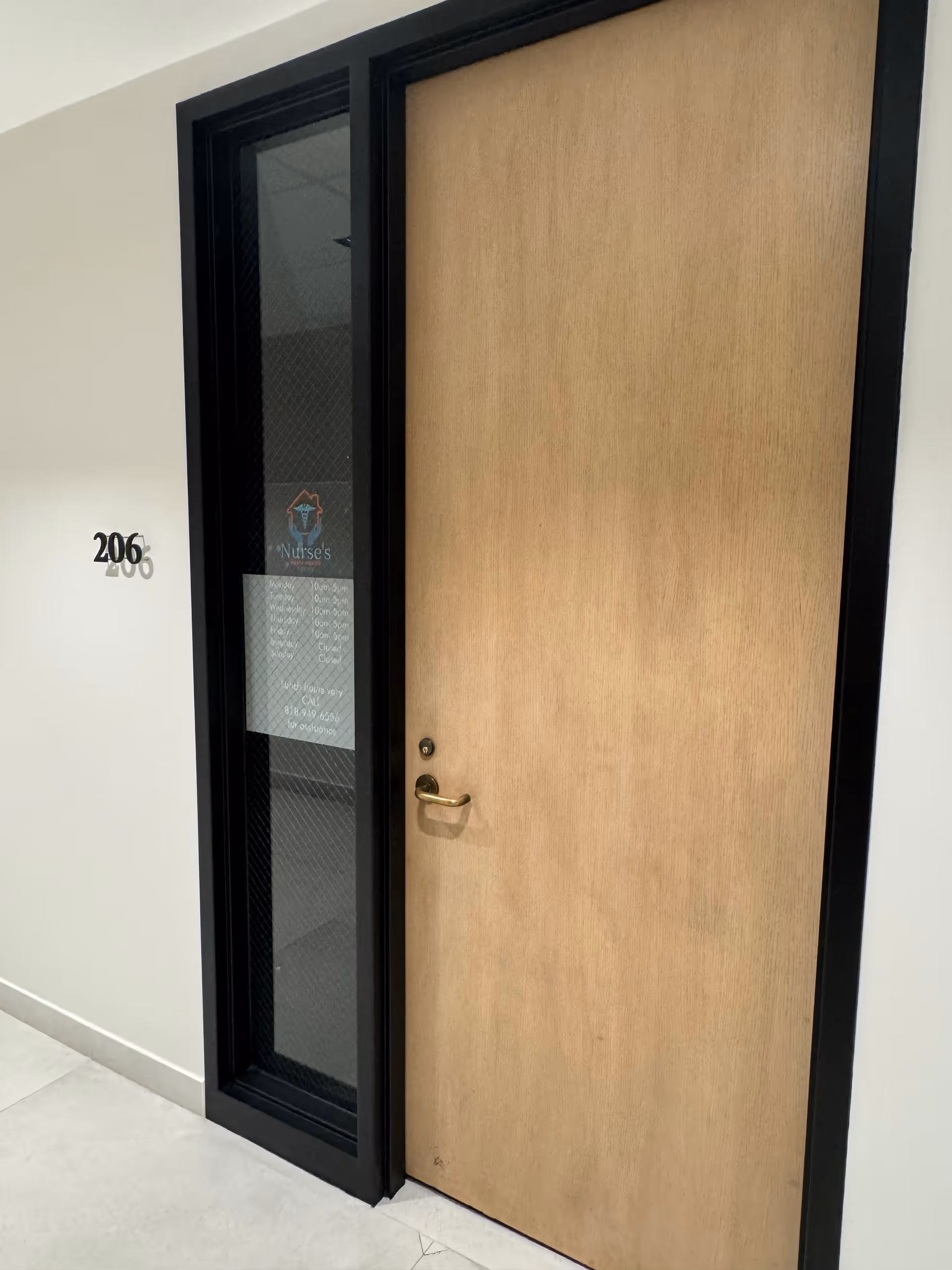 Wooden interior door beside a glass entry panel labeled with unit 206.