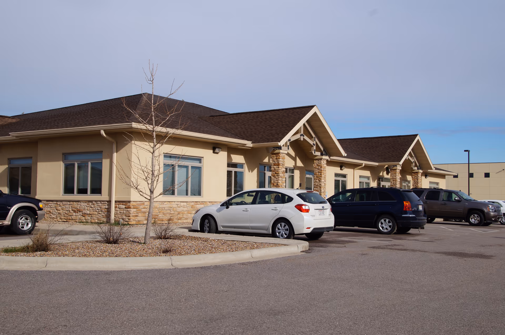 Single-story senior living facility with beige facade and parked cars in the lot.