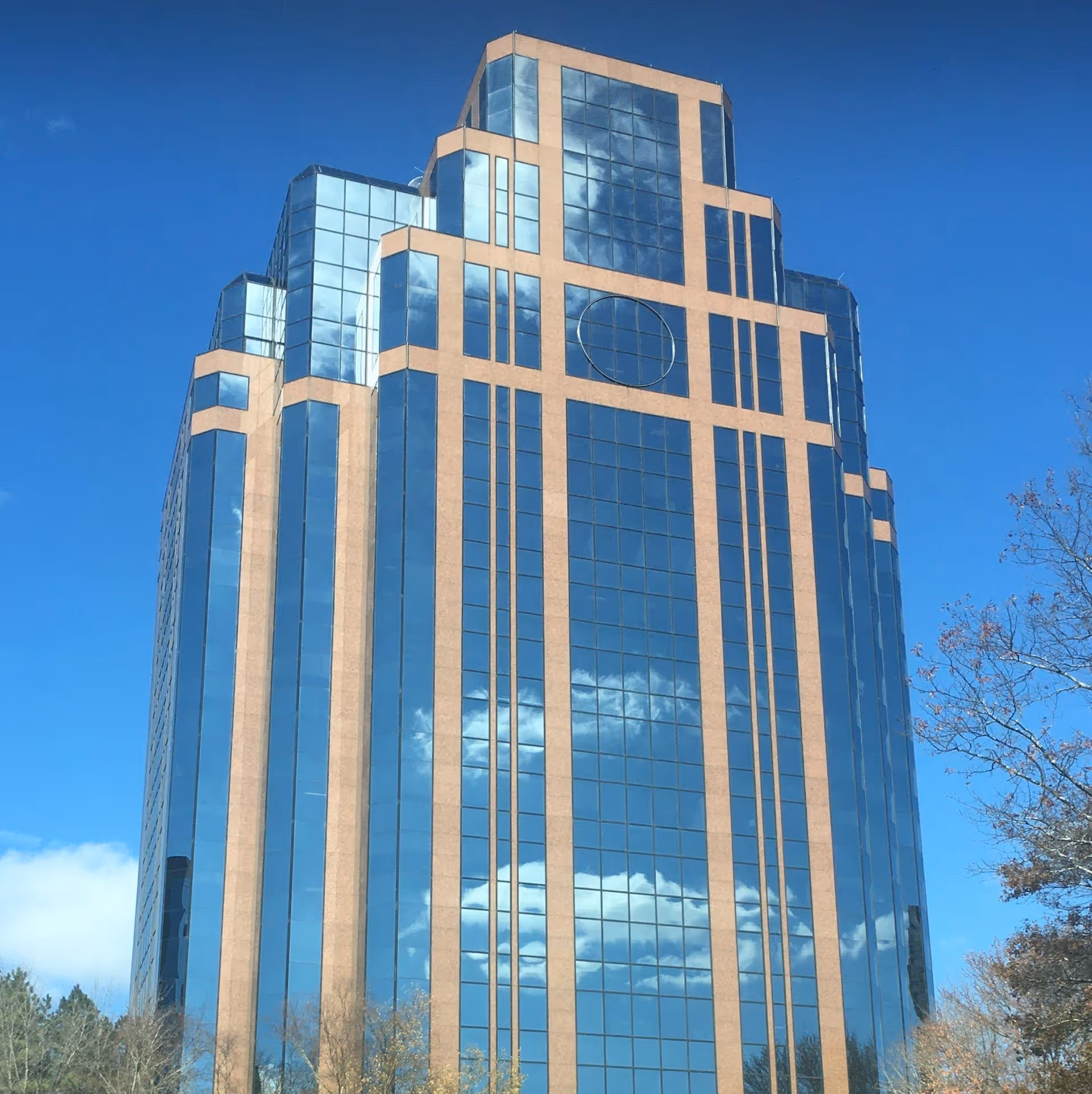 Tall modern glass office building with blue reflective windows against a clear sky