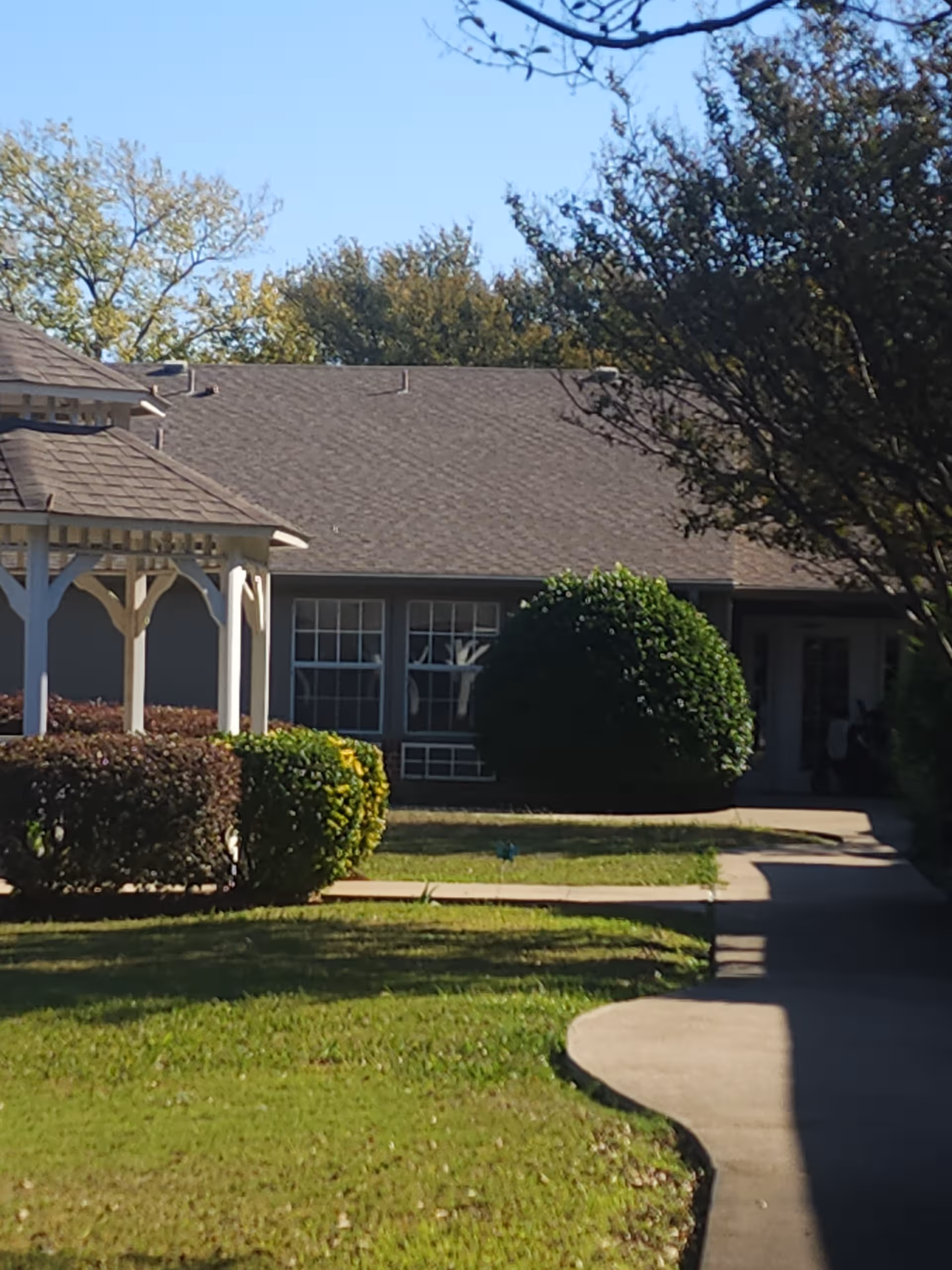 Exterior view of Castle Rock Assisted Living entrance with walkway and shrubs.