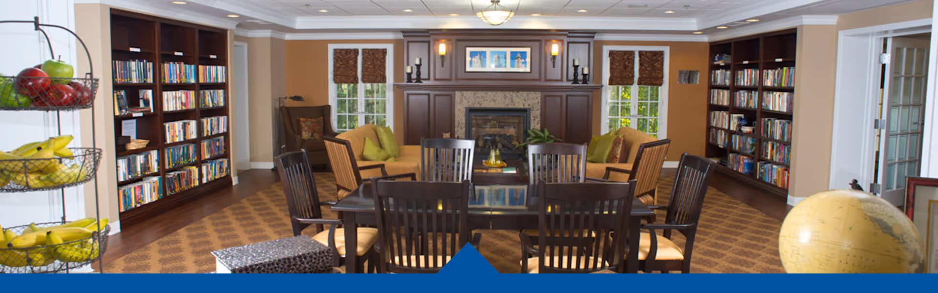 A spacious living room with bookshelves, a fireplace, and comfortable seating.