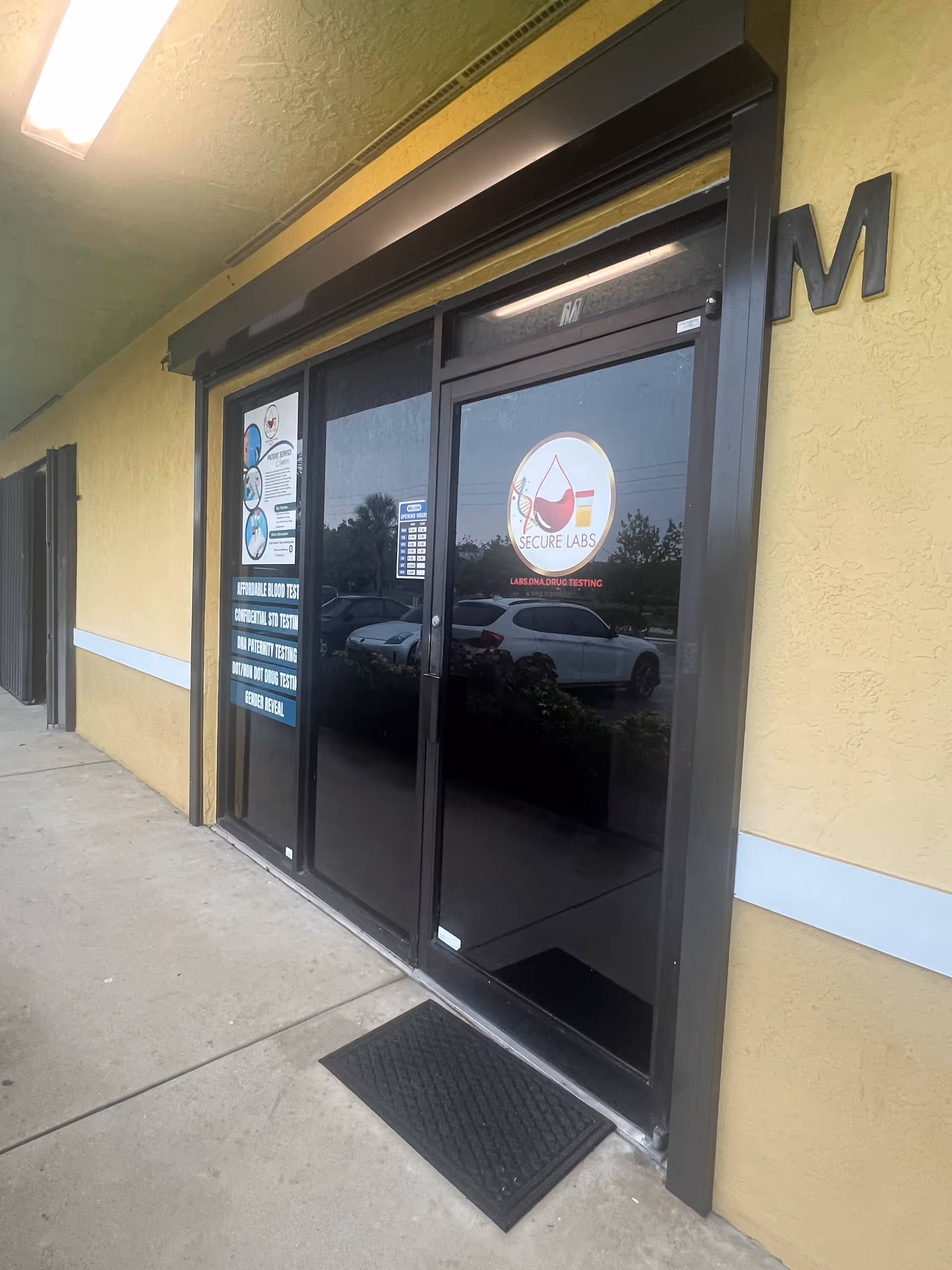 Exterior entrance with glass doors labeled Secure Labs on a yellow stucco building.