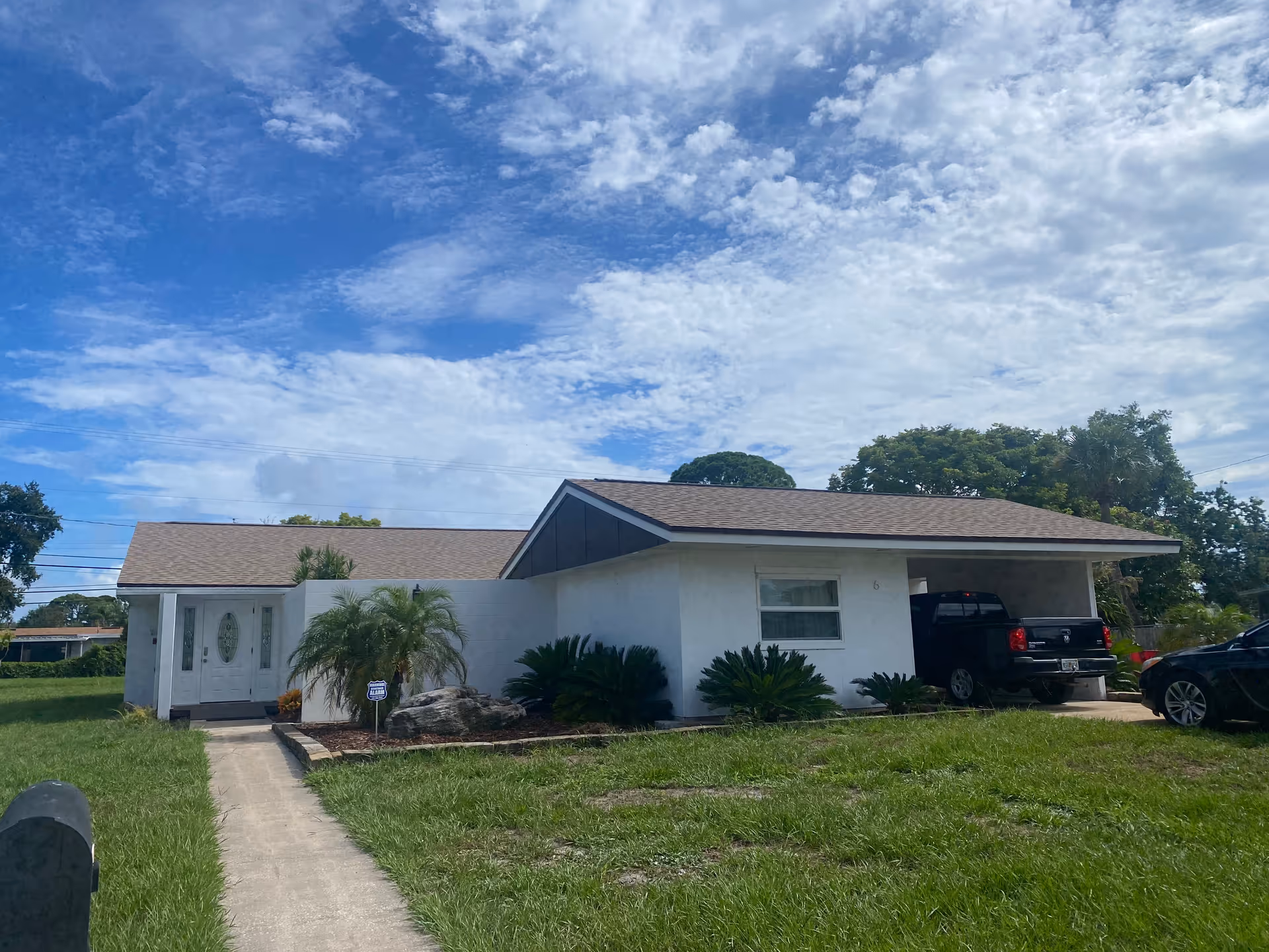Front view of a single-story white building with a carport and green lawn.