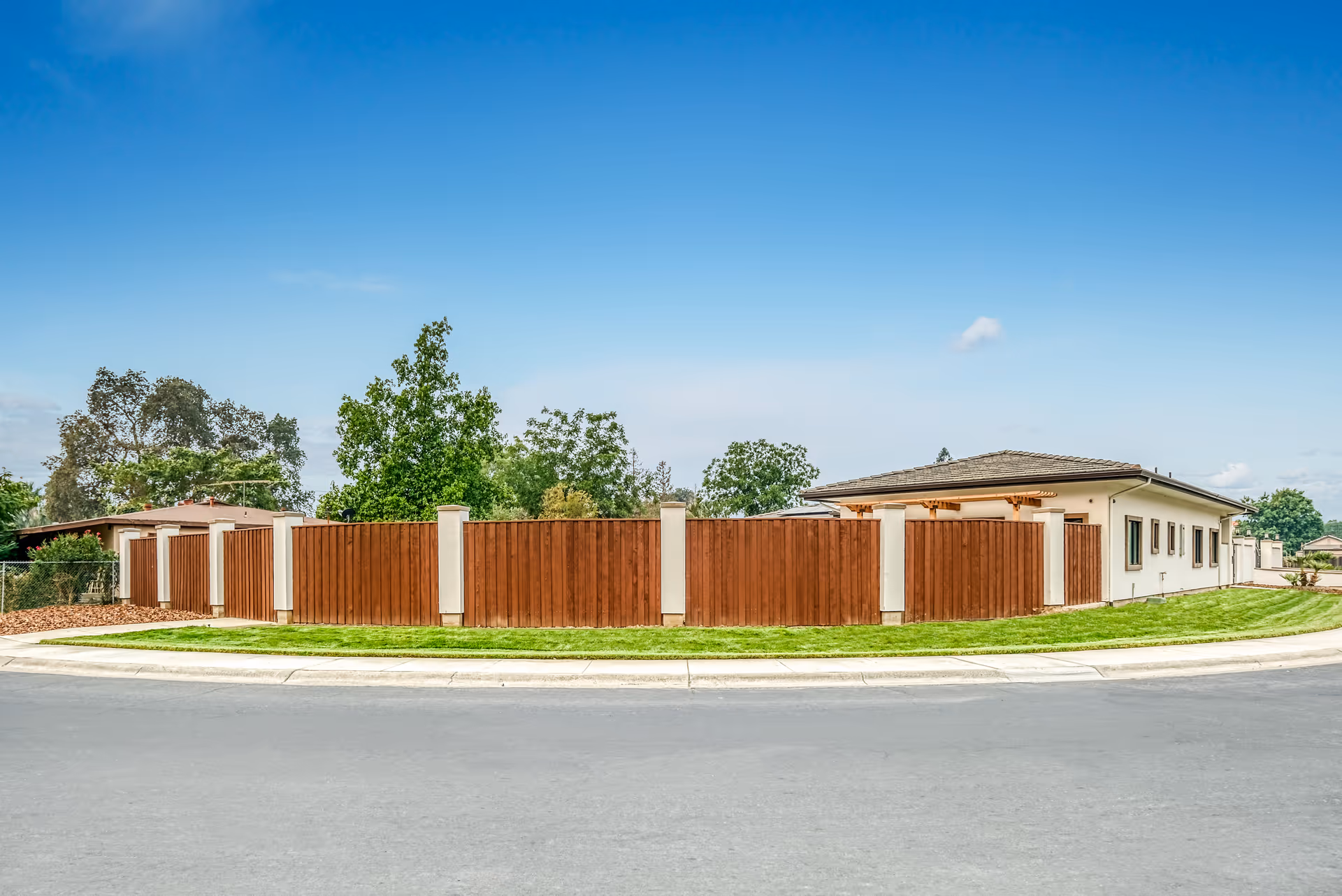 Exterior view of a nursing center surrounded by a brown wooden fence along a curved street.
